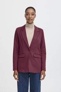 Bourgogne kavaj med skräddarsydd design, enknappsslutning och två framfickor, kombinerad med en ljus polotröja och blå jeans.