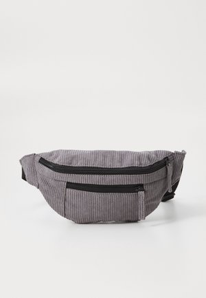 Sac banane en tissu velours côtelé gris avec deux poches à fermeture éclair noires et une sangle ajustable sur fond blanc uni.