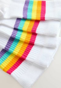 Hvide sokker med vandrette striber i lilla, turkis, gul og pink. Texturen er ribbet over hele sokken med kontrastfarver.