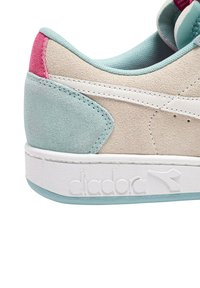 Sneaker in suede beige con dettagli in teal e rosa, suola in gomma bianca e cuciture a vista. Logo impresso sul lato.