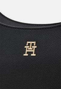 Schwarze, strukturierte Lederhandtasche mit einem Monogramm-Logo in Goldfarbe. Verfügt über glatte Kanten und subtile Steppdetails.