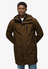 Brązowa wodoodporna parka z kapturem, z zamykanymi na zamek kieszeniami i minimalistycznym designem, wykonana z gładkiego, trwałego materiału. Zapięcie z przodu na zamek.