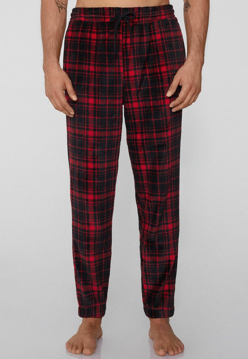 Červené a černé kárované flísové pyžamové kalhoty s elastickým pasem a šňůrkou, s volným střihem a jednobarevnými manžetami.