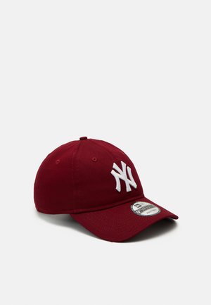 Punainen baseball-lippis, joka on tehty puuvillasta ja jossa on valkoinen brodeerattu logo sekä säädettävä hihna takana, kaarevalla lippaalla.