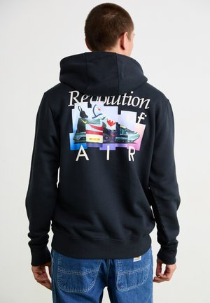 Hoodie noir avec des graphiques colorés de baskets dans le dos, accompagné du texte "Révolution de l'AIR" dans une police claire, et des poignets et un ourlet côtelés.