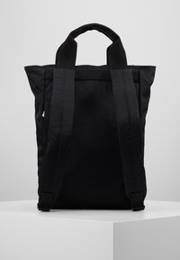 Zwarte stoffen rugzak met dubbele handgrepen, gevoerde banden, gestructureerd materiaal en minimalistisch ontwerp. Zijvak en versterkte bodem.