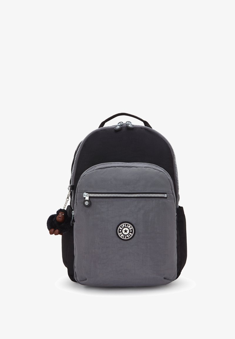 Grijze en zwarte nylon rugzak met dubbele ritscompartimenten, voorzien van een logopatch en een klein aapje sleutelhangeraccessoire.