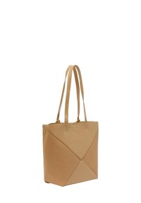 Täckväska i tan-färg med en texturerad yta och släta accenter. Har en geometrisk design med fyra triangulära sektioner och två långa handtag.