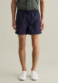 Costumi da bagno blu navy realizzati in tessuto leggero, con vita elasticizzata e coulisse, e tasche laterali per comodità.