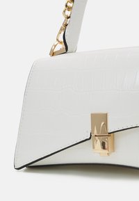 Weiße Handtasche aus Lederimitat mit Kroko-Prägung, strukturierter Form, goldfarbener Hardware und Ketten-Schulterriemen. Mit einem geometrischen Verschlussdetail.