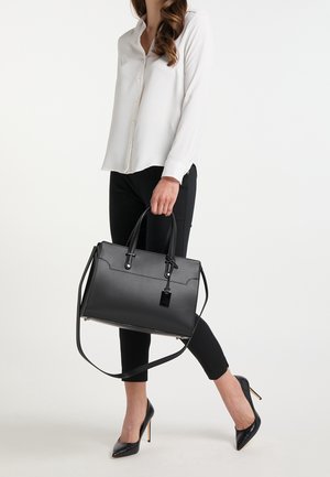Sac à main en cuir noir avec double poignée, bandoulière amovible et ferrures argentées. Texture lisse et forme rectangulaire structurée.