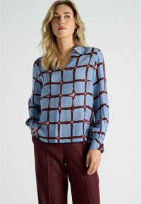 Blauwe blouse met patroon in een ruitdesign in bordeauxrood. Heeft lange mouwen met gather aan de manchetten en een v-hals. Gladde stofstructuur.