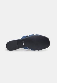 Sandale en tissu bleu avec une semelle en caoutchouc noir texturé, dotée de deux larges sangles et d'un logo discret sur la semelle intérieure.