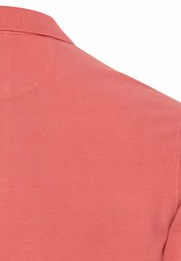 Koraalkleurig poloshirt van een gebreide stof met structuur. Voorzien van een klassieke kraag en korte mouwen, met een soepele, uniforme uitstraling.
