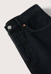 Jeans de mezclilla negra con un acabado texturizado, presentando un botón plateado y un remache con acentos de cobre, angulados para una vista detallada de la cinturilla.