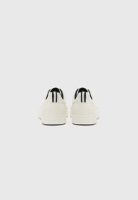 White sneakers with a smooth upper, featuring black striped accents on the back. Thick sole with a textured finish, designed for comfort.