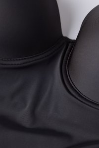 Sujetador negro acolchado con tejido liso y mate con un brillo sutil; copas redondeadas y costuras limpias a lo largo de los bordes.