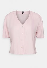 Krátký rukáv, blůza s V výstřihem z světle růžové látky s knoflíkovou légou, která má kulaté stříbrné knoflíky. Hladká struktura, zkrácený střih.