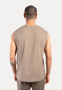 Muskel-Tanktop aus hellbraunem Stoff, ärmelloses Design, glatte Textur und runder Ausschnitt, das eine lässige Passform zeigt.