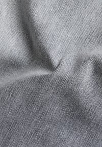 Tejido de mezclilla gris con una textura suave, que presenta un sutil degradado y un patrón de tejido. Material blando y flexible con un ligero brillo.