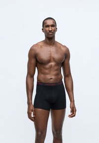 Fekete boxer alsónadrág piros "BJÖRN BORG" derékkal. Simáló anyagból készült, fitted kialakítással és rövid lábhosszal rendelkezik.