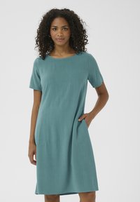 Ärmelloses tealfarbenes Kleid, knielang, gerader Schnitt, weiche Textur, mit seitlichen Taschen und einem einfachen runden Ausschnitt.