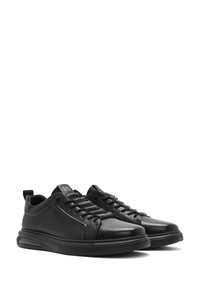 Sneaker nere con tomaia in pelle liscia, punta rotonda, chiusura con lacci e colletto imbottito. Presentano una suola leggera con ammortizzazione ad aria.