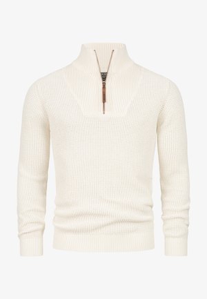 Crèmekleurige gebreide sweater met een halve ritskraag, geribbelde textuur en strakke manchetten. De stof heeft een wafelpatroon.