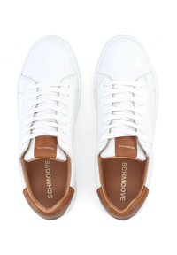 White leather sneakers with flat laces, brown leather accents at the heel, and a tan interior. Features logo on the insole.