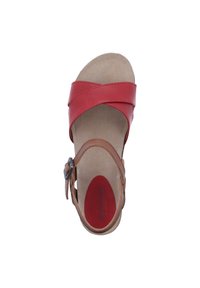 Red leather sandal with cross-strap design, featuring a brown ankle strap and a textured beige footbed. Red logo visible on insole.