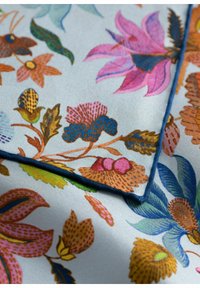 Tissu floral coloré avec un fond bleu clair. Présente des motifs complexes de fleurs roses, rouges, dorées et vertes, avec une bordure bleue.