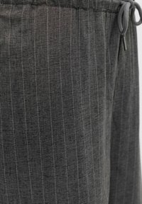 Pantaloni grigi con un motivo a righe, realizzati in tessuto testurizzato. Presentano un cinturino elastico e un cordino per una vestibilità regolabile.