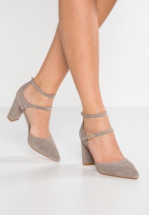 Grey suede high-heeled shoes with an ankle strap, pointed toe, and block heel design. Smooth texture with a minimalistic style.
