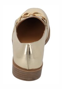 Scarpa d'oro metallico con punta arrotondata, texture liscia e un accento decorativo a catena sul retro. Caratterizzata da un tacco impilato marrone.