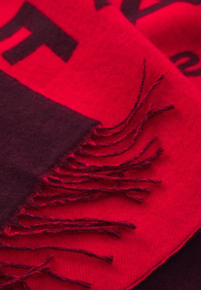 Écharpe rouge et bordeaux foncé avec une texture douce. Présente des bords frangés et des lettres en gras. Les couleurs contrastées créent une apparence en couches.