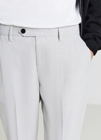 Hellegraue strukturierte Hose mit geradem Schnitt, ausgestattet mit einem schwarzen Knopfverschluss, seitlichen Taschen und dezenten Bügelfalten.