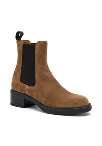 Bottine en daim marron avec panneaux latéraux élastiques, semelle en caoutchouc noir, bout arrondi et accents texturés contrastants. Comprend une boucle au talon.