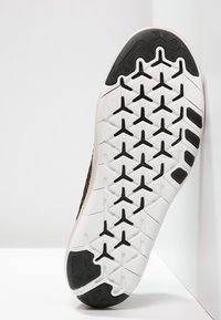 Suola di scarpa sportiva nera con una base in gomma bianca testurizzata e un distinto motivo di trazione, accentuata da un bordo rosa pallido liscio.
