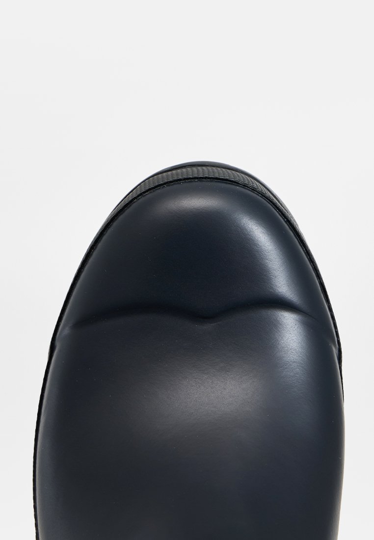 Schwarzer Leder-Schuh mit abgerundetem Zehenbereich, glatter Textur, dezenten Nähten und einer dicken Sohle mit Gummi-Grip entlang der Kante.