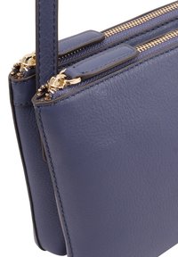 Marine leren handtas met dubbele ritssluiting, goudkleurige hardware en textuurafwerking. Compact rechthoekig ontwerp met verstelbare banden.