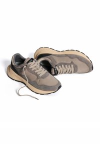 Zapatillas de ante gris con suela de goma beige, presentan cordones blancos, punta redondeada y un branding mínimo en la lengüeta y el costado.