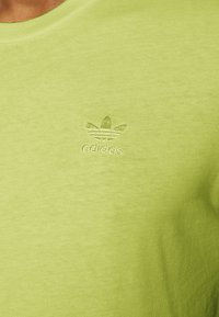 Maglietta in cotone verde lime con collo rotondo, dotata di un logo Adidas ricamato in una tonalità abbinata sull'area sinistra del petto.