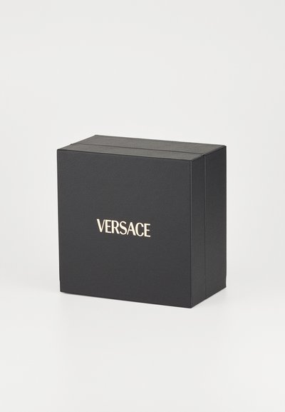 Juodas kartoninis dėžutė su tekstūruota paviršiumi. Priekyje yra auksinis "VERSACE" logotipas. Stačiakampio formos su pakeliamomis durelėmis.