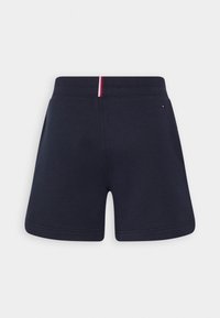 Pantalones cortos deportivos azul marino con una textura suave, cinturilla elástica con un acento a rayas rojas y blancas en la parte posterior.