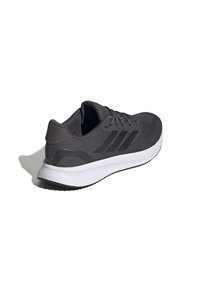 Scarpa da corsa grigia scura con parte superiore testurizzata, tre strisce nere e suola bianca. Presenta un collo imbottito e design con lacci.