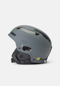 Casco de esquí gris con acabado mate, aberturas de ventilación, sistema de ajuste ajustable y tecnología MIPS para mayor seguridad.