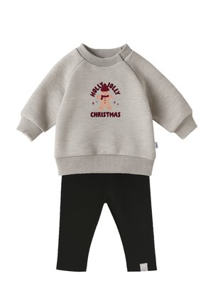 Hellgrauer Pullover mit Aufdruck "Holly Jolly Christmas" und Rentier-Design; kombiniert mit schwarzen, gerippten Leggings.