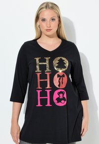 Svart tunika med trekvartsärmar som har metallisk och glittrig "HO HO HO" text i guld, rosa och pink. Mjuk bomullsmaterial.