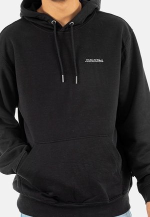 Persoon die een zwarte Dickies-hoodie draagt met een voorzak en trekkoorden, getoond van nek tot taille tegen een witte achtergrond.