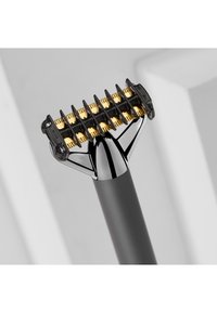 Svart og gull hårklipper med et bredt klippehode, som har åtte gullbelagte skjærekantene og et stilrent svart håndtak.